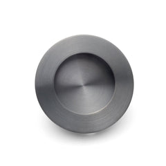 A gunmetal round flush pull for sliding doors with a visible textured surface and a central sunken area.