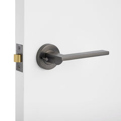 Modern door handle on a white door with a light gray background