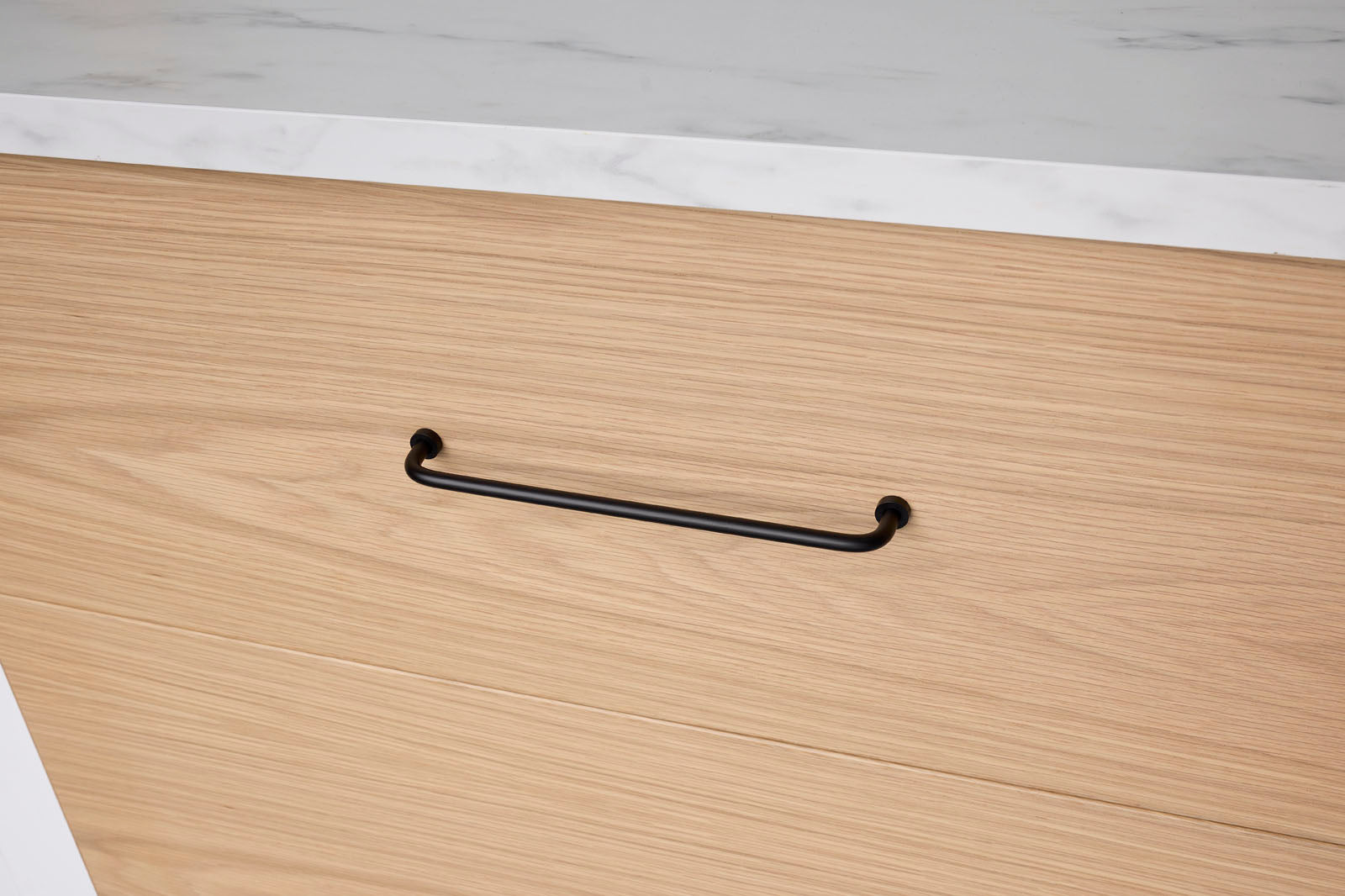 Wooden surface with a black handle on a light-colored floor.