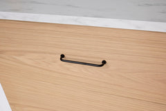 Wooden drawer with a black handle on a light wooden surface.